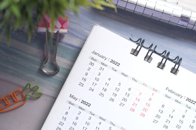 A 2022 desk calendar with colored clips and a pen on a wooden desk.